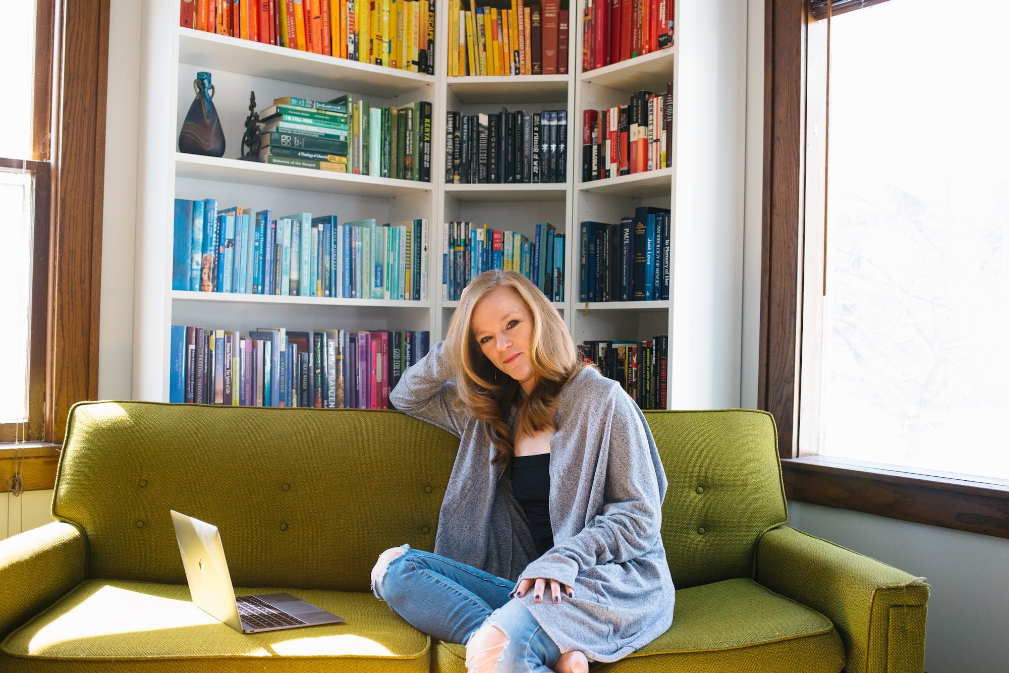 Ellie Roscher sitting on a couch in front of a shelf full of books